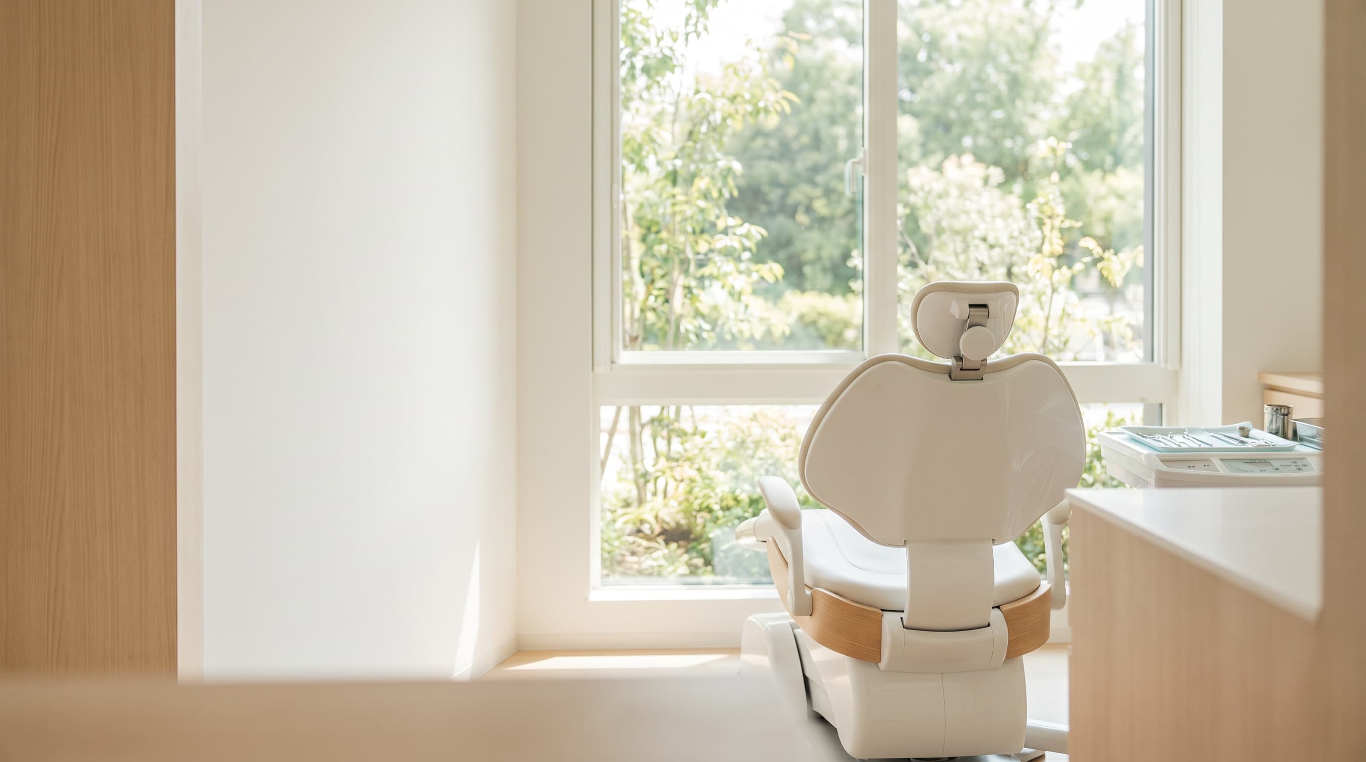Sala de tratamiento dental impecable, en blanco y madera clara, con luz natural